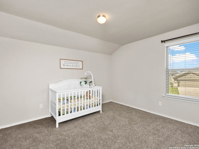 carpeted bedroom with a crib and vaulted ceiling