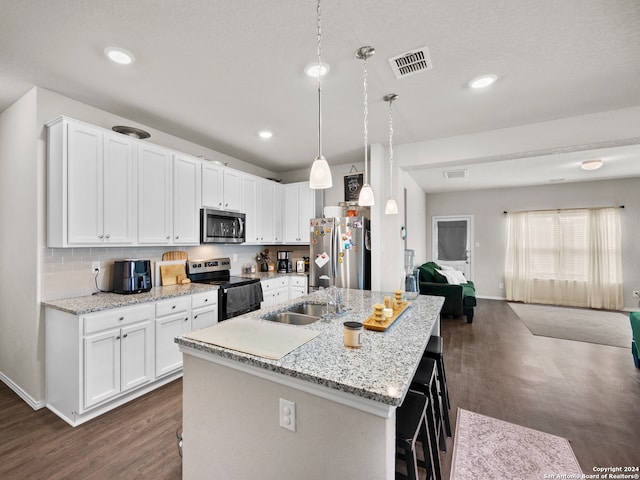 kitchen featuring white cabinetry, dark wood-type flooring, pendant lighting, a kitchen island with sink, and appliances with stainless steel finishes