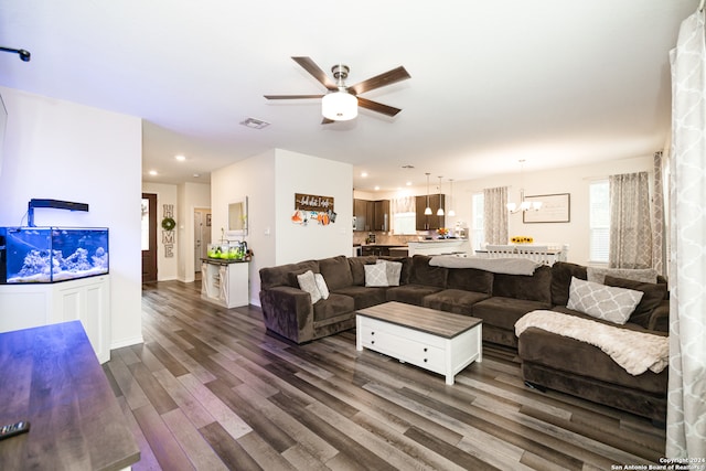 living room featuring dark wood-type flooring and ceiling fan with notable chandelier