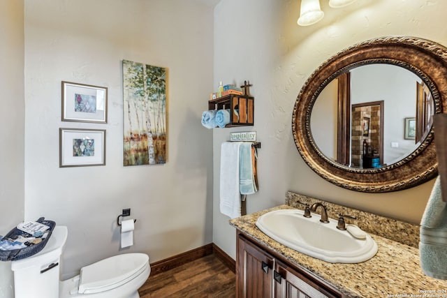 bathroom with toilet, vanity, and hardwood / wood-style flooring