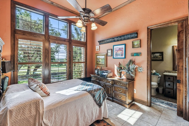 bedroom featuring multiple windows, ceiling fan, ensuite bath, and light tile patterned floors