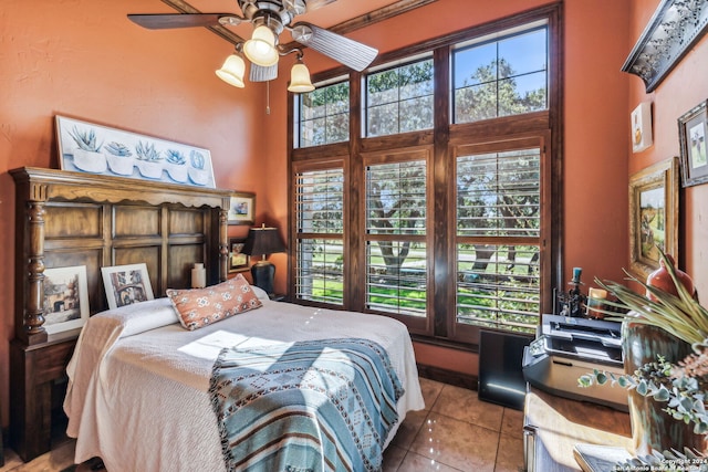 tiled bedroom with ceiling fan and a high ceiling