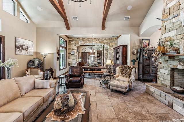 living room with beam ceiling, an inviting chandelier, high vaulted ceiling, and a stone fireplace