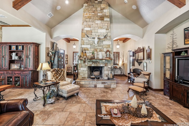 living room with beam ceiling, high vaulted ceiling, and a stone fireplace