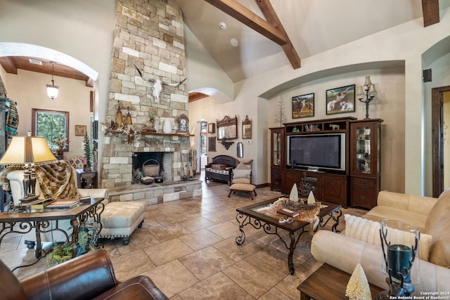 living room with beam ceiling, a stone fireplace, and high vaulted ceiling