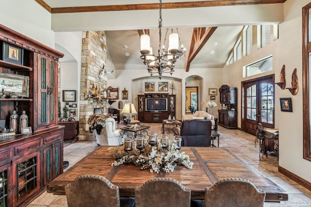 dining space with beam ceiling, french doors, an inviting chandelier, high vaulted ceiling, and a fireplace