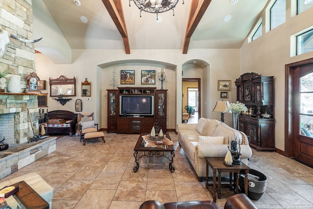 living room featuring beamed ceiling, a fireplace, high vaulted ceiling, and a chandelier