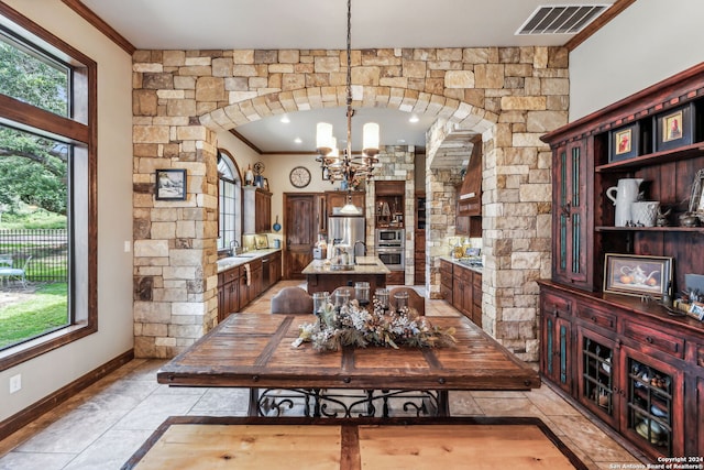 dining room featuring light tile patterned flooring, an inviting chandelier, ornamental molding, and sink