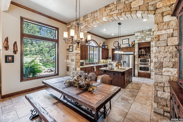 tiled dining space featuring sink, a chandelier, and ornamental molding