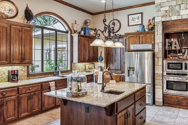 kitchen featuring appliances with stainless steel finishes, tasteful backsplash, sink, decorative light fixtures, and an island with sink