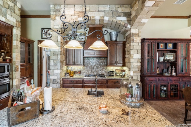 kitchen with light stone countertops, stainless steel appliances, and decorative light fixtures