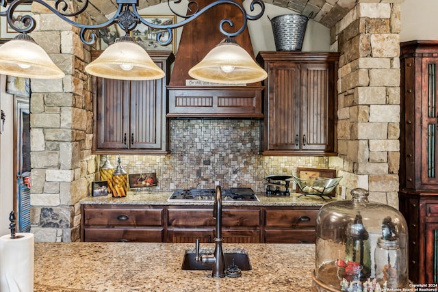 kitchen featuring tasteful backsplash, dark brown cabinetry, light stone countertops, and stainless steel gas cooktop