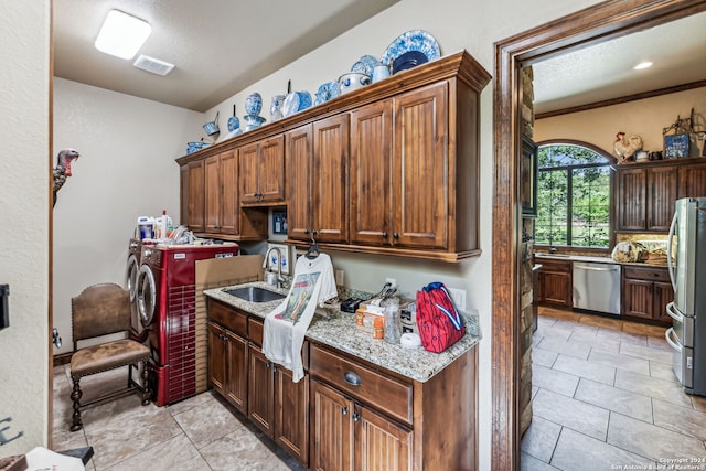 interior space with sink, light stone countertops, a textured ceiling, stainless steel appliances, and washing machine and clothes dryer