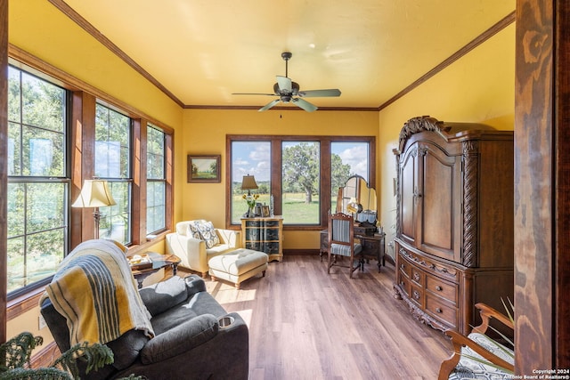 living area with a wealth of natural light, hardwood / wood-style floors, ceiling fan, and crown molding