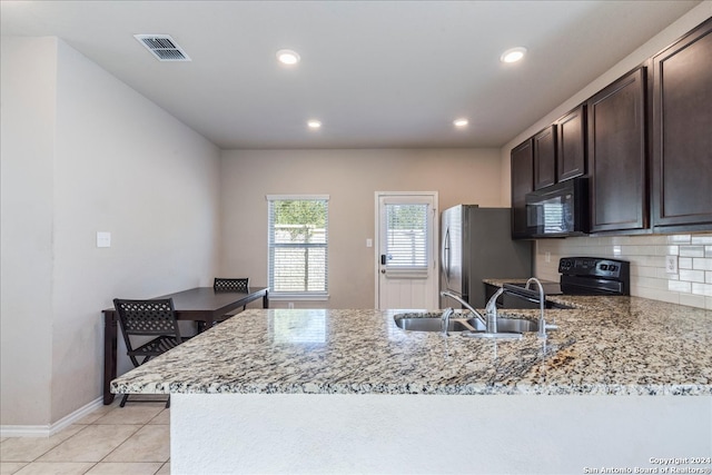 kitchen with backsplash, black appliances, sink, dark brown cabinets, and light stone counters