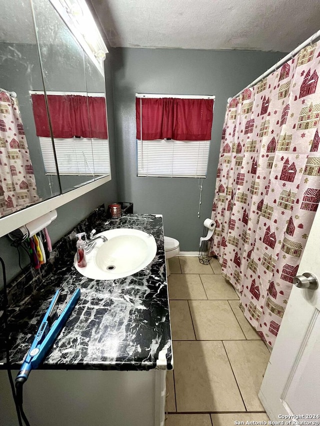 bathroom with tile patterned floors, vanity, toilet, and a textured ceiling