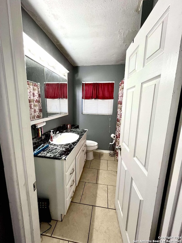 bathroom with tile patterned floors, vanity, a textured ceiling, and toilet