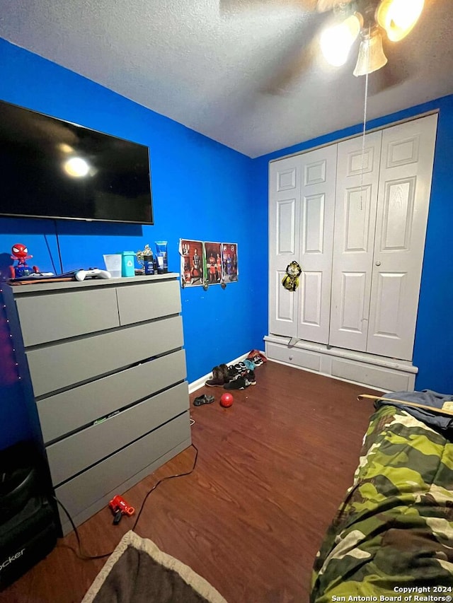 bedroom featuring ceiling fan, dark hardwood / wood-style flooring, a textured ceiling, and a closet