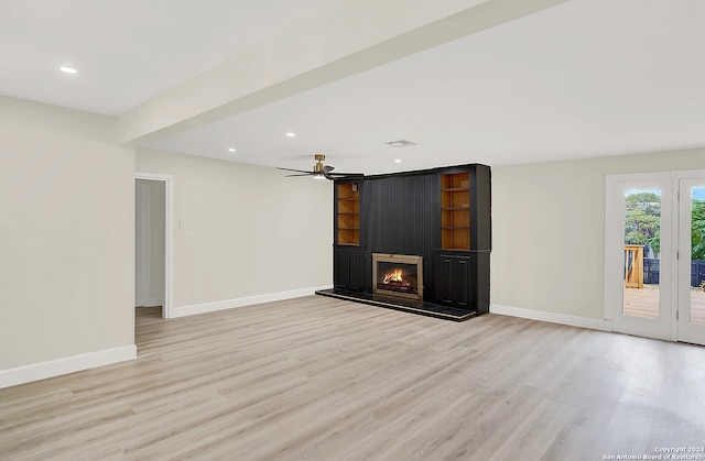 unfurnished living room featuring light wood-type flooring, a large fireplace, and ceiling fan