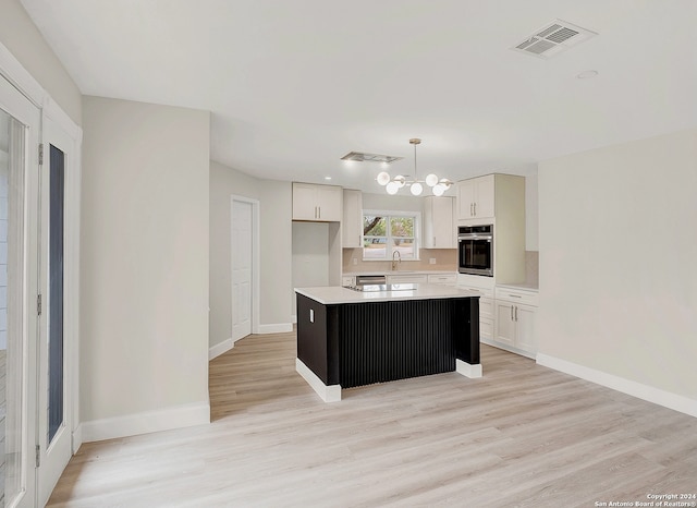 kitchen with white cabinets, a center island, oven, and decorative light fixtures