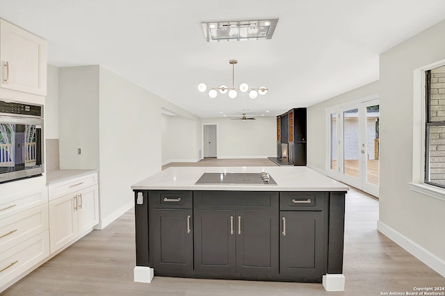 kitchen with a center island, stainless steel oven, black electric cooktop, white cabinets, and light wood-type flooring