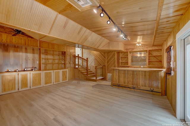 interior space featuring wood walls, built in features, vaulted ceiling, and light hardwood / wood-style flooring