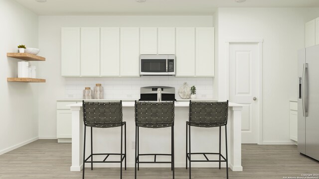 kitchen with decorative backsplash, white cabinets, stainless steel appliances, and light wood-type flooring