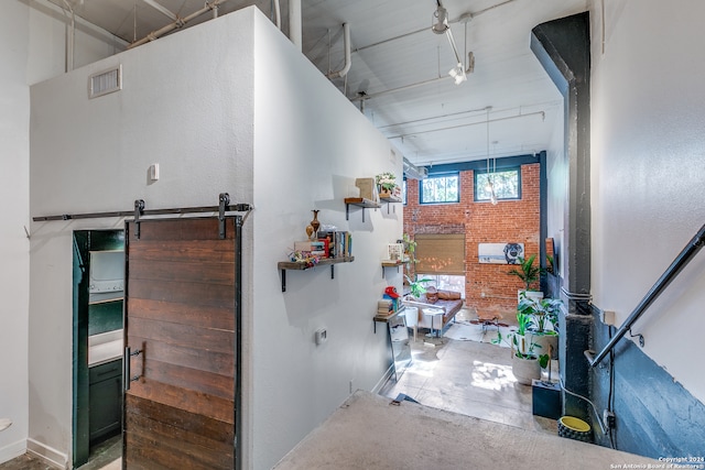 interior space featuring a barn door and brick wall