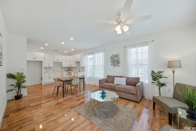 living room with ceiling fan, sink, and light hardwood / wood-style floors