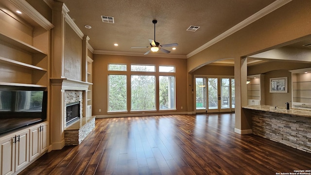 unfurnished living room featuring a textured ceiling, built in shelves, a fireplace, and visible vents