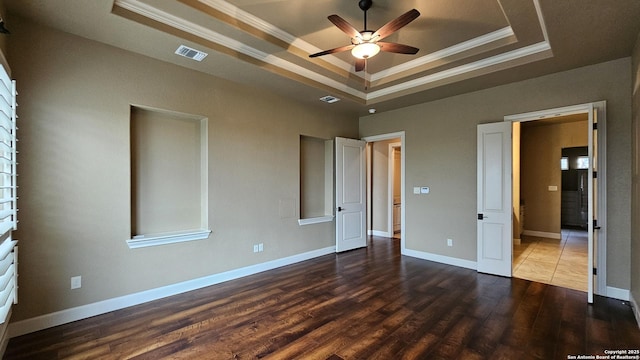 unfurnished bedroom with a raised ceiling, visible vents, crown molding, and wood finished floors