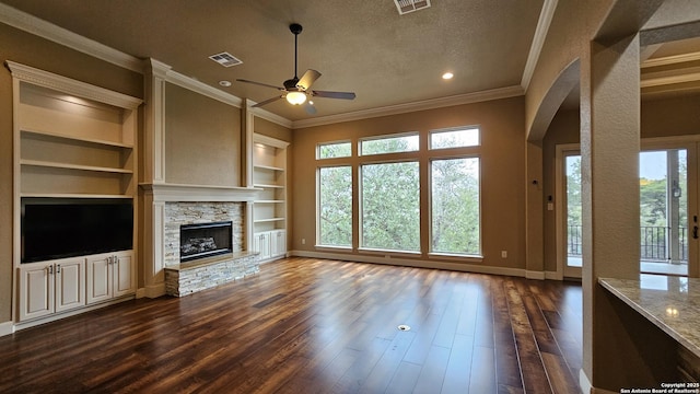 unfurnished living room with visible vents, crown molding, a stone fireplace, a textured ceiling, and dark wood-style flooring