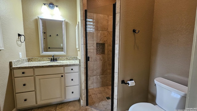 bathroom with a stall shower, a textured wall, vanity, and toilet