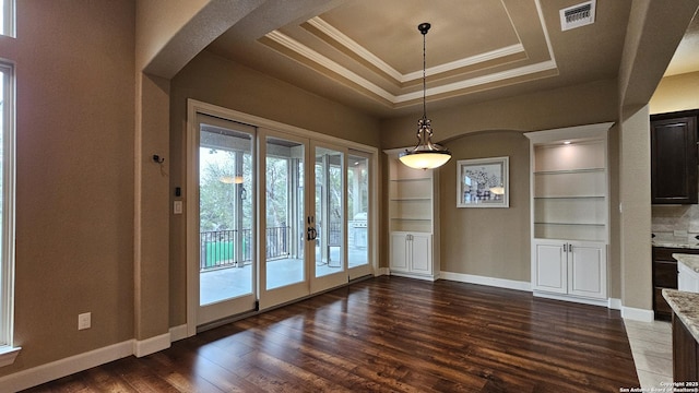 unfurnished dining area with dark wood-type flooring, visible vents, french doors, a tray ceiling, and crown molding