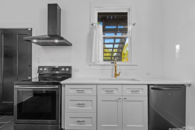 kitchen with white cabinetry, wall chimney range hood, sink, and appliances with stainless steel finishes