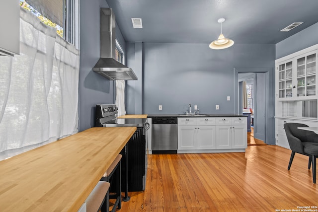 kitchen with wooden counters, white cabinetry, stainless steel dishwasher, and light hardwood / wood-style flooring