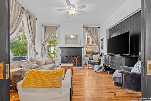 living room with hardwood / wood-style flooring, ceiling fan, and a tile fireplace