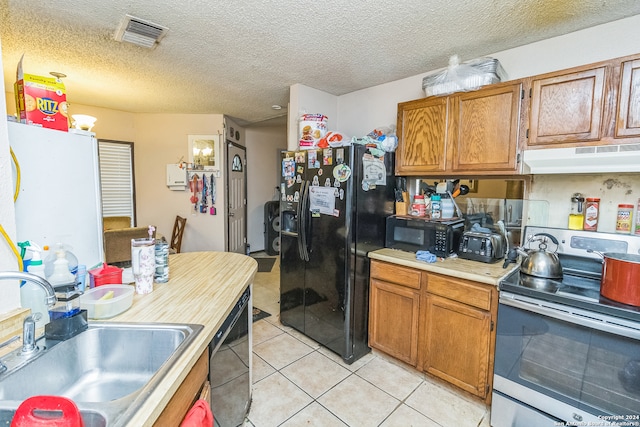 kitchen with sink, ventilation hood, a textured ceiling, light tile patterned flooring, and black appliances