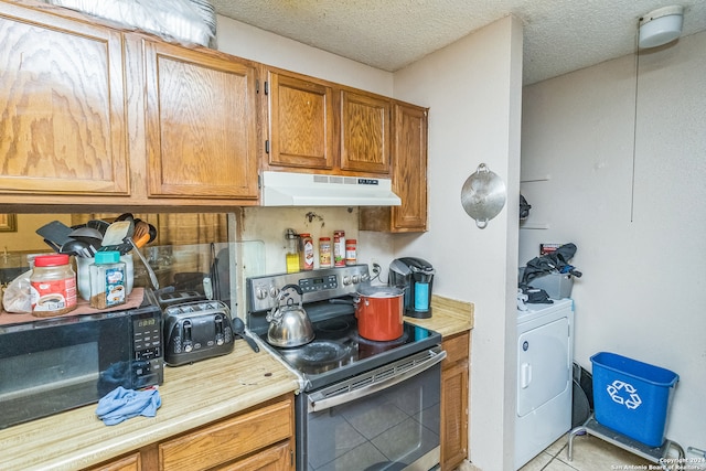 kitchen featuring a textured ceiling, light tile patterned floors, stainless steel electric range, and washer / dryer