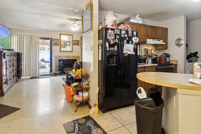 kitchen with a tile fireplace, ceiling fan, black appliances, and a textured ceiling