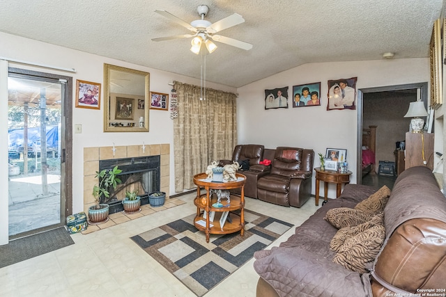 living room featuring a textured ceiling, ceiling fan, a fireplace, and vaulted ceiling