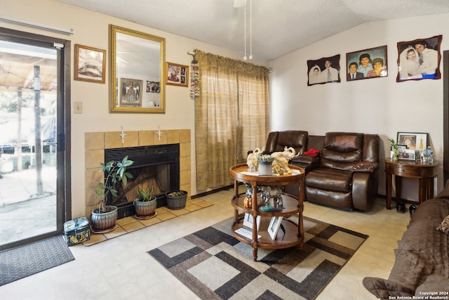 living room featuring a textured ceiling, a tile fireplace, and vaulted ceiling