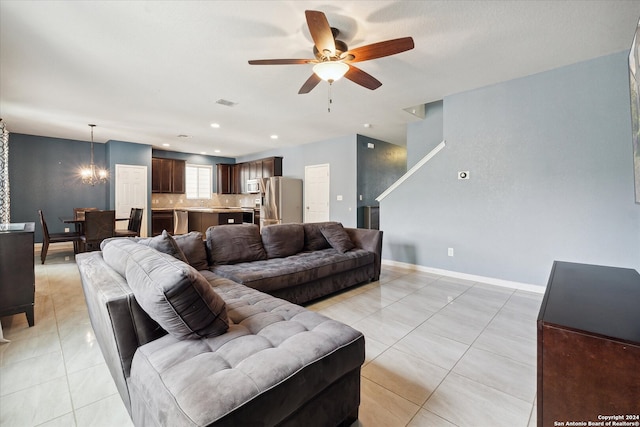 living room with light tile patterned flooring and ceiling fan with notable chandelier