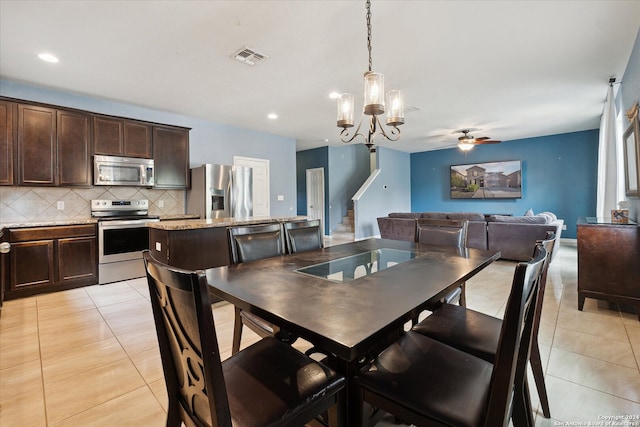 dining area featuring light tile patterned floors and ceiling fan with notable chandelier