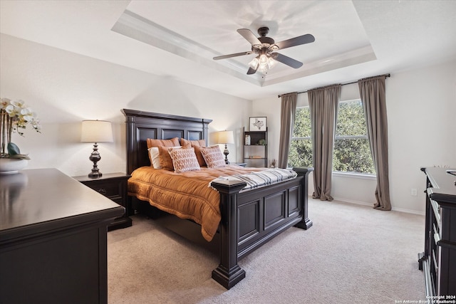 carpeted bedroom with a tray ceiling and ceiling fan