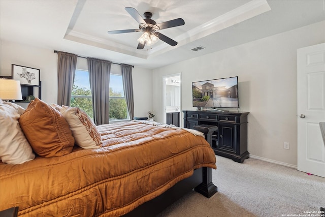 bedroom featuring ceiling fan, a raised ceiling, light carpet, and connected bathroom