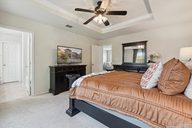 carpeted bedroom with a tray ceiling and ceiling fan