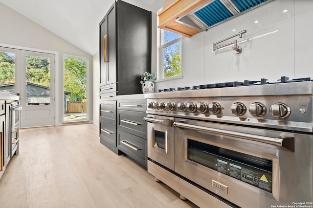 kitchen featuring vaulted ceiling, light hardwood / wood-style floors, range with two ovens, and range hood