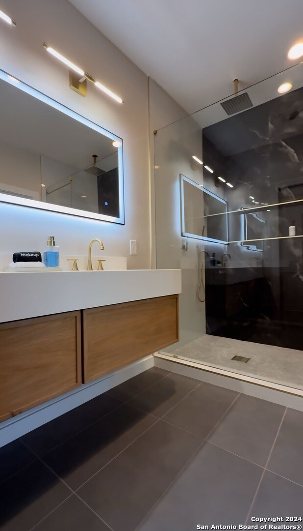 bathroom with a shower, tile patterned flooring, and vanity