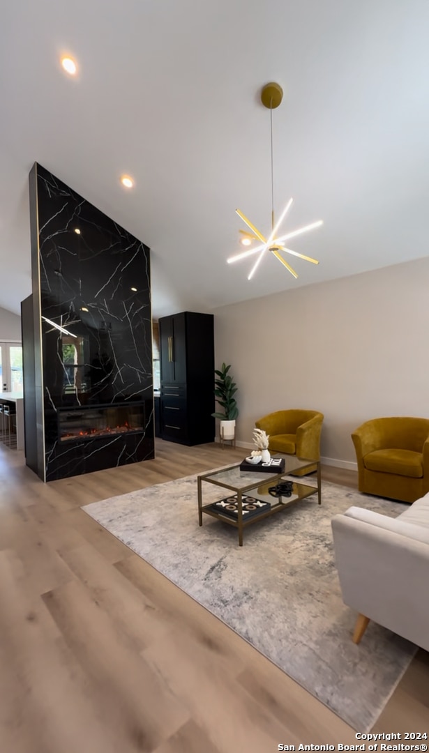 living room featuring hardwood / wood-style flooring, a notable chandelier, lofted ceiling, and a fireplace